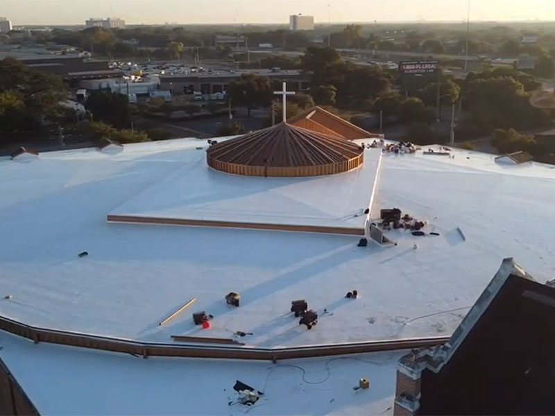 Top view of the circular commercial roof of a church with a brand new white single-ply system installed by Arica Roofing & Construction LLC